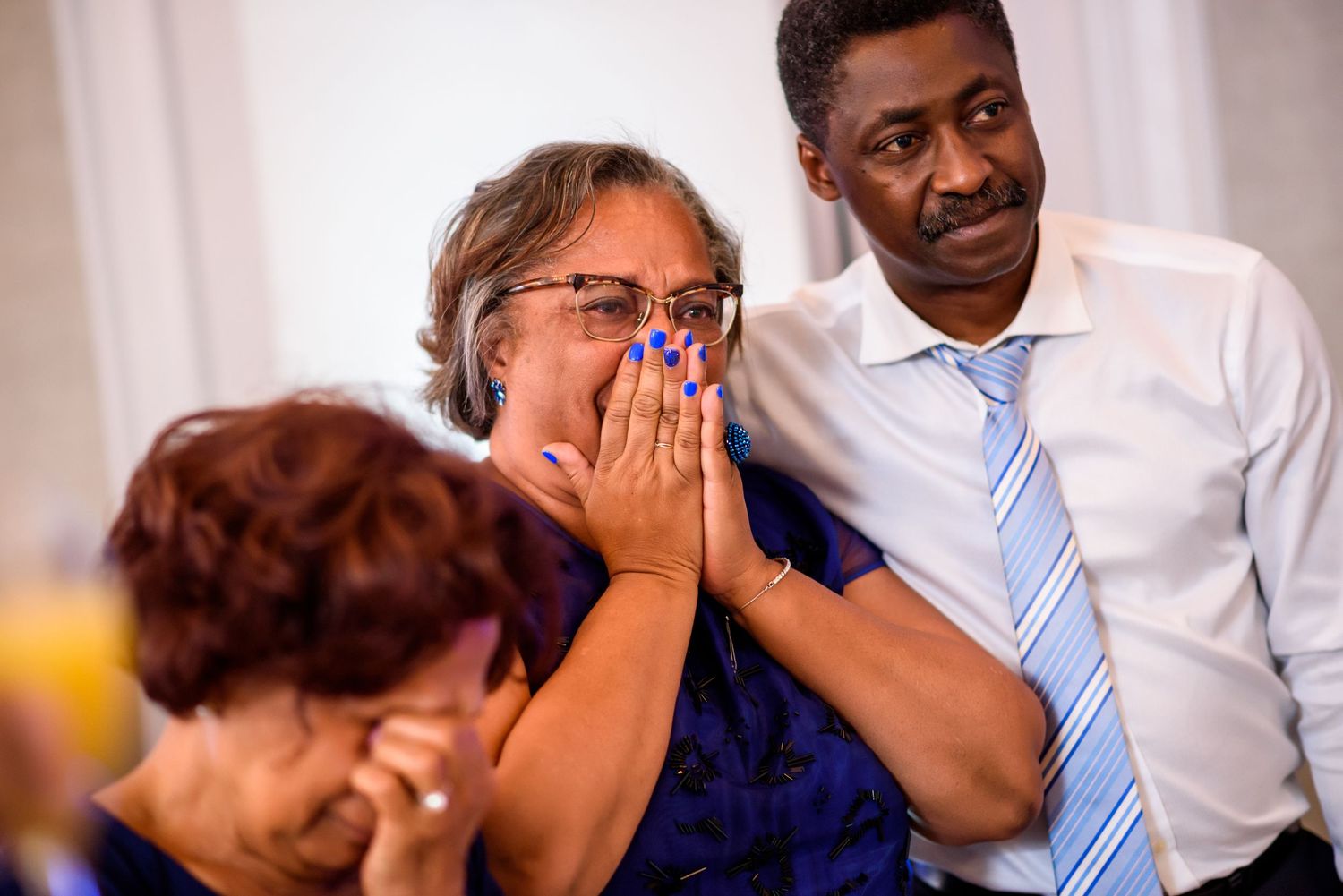Emotional wedding reception scene with guests wiping tears during heartfelt speeches.