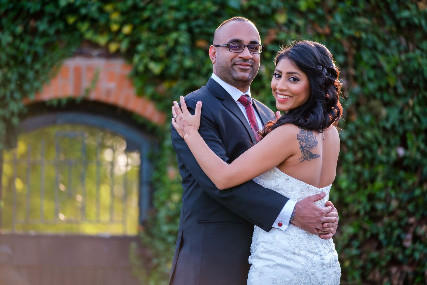 Romantic outdoor wedding portraits against a lush green ivy wall backdrop.