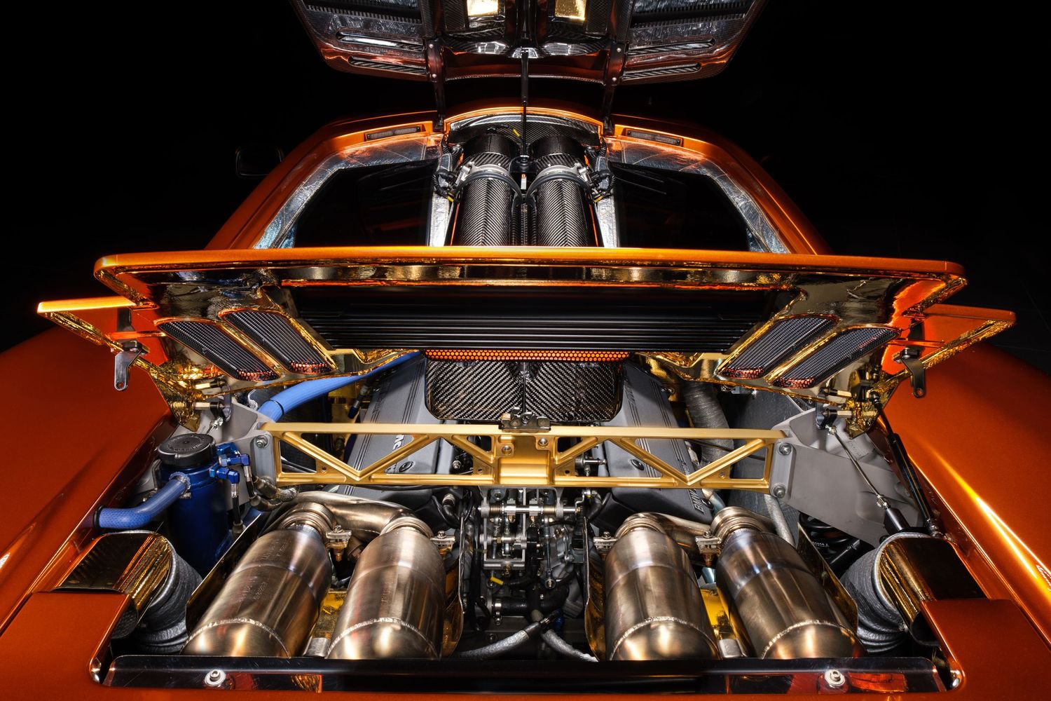 Detailed view of an orange McLaren's engine bay revealing its high-performance powertrain components.