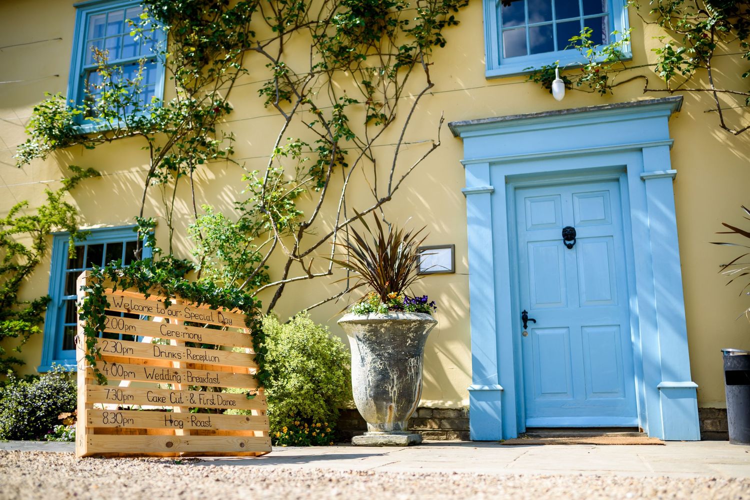 A charming cottage exterior with light blue shutters, climbing vines, and rustic brick details against cream colored walls.