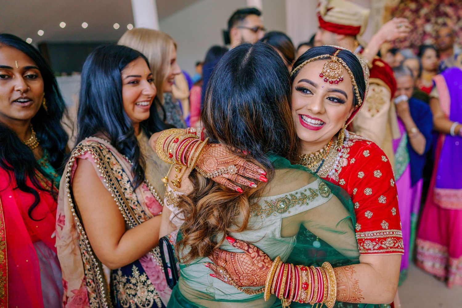 Colorful celebration at an Indian wedding with guests wearing vibrant traditional attire and jewelry.