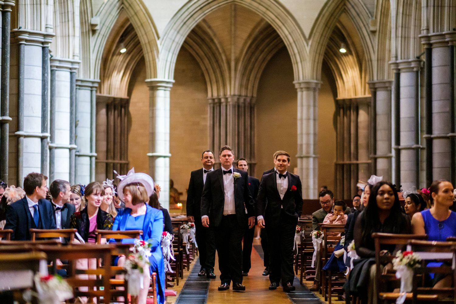 Majestic stone cathedral interior with Gothic arches and rows of seated wedding guests.