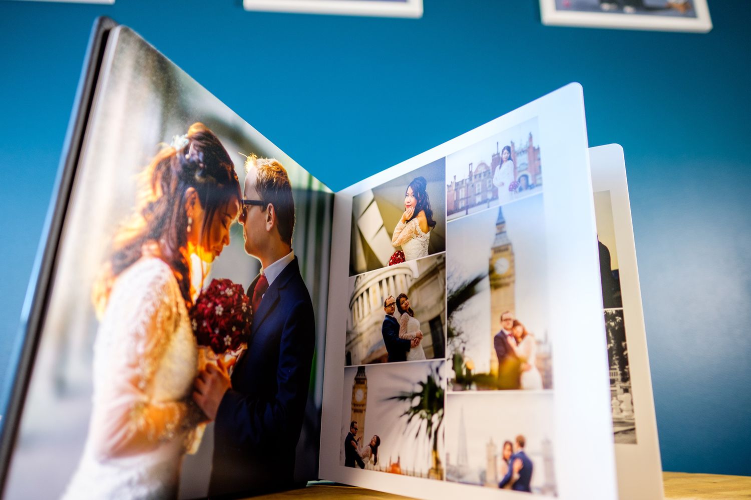 Open photo album displaying wedding photography spreads against blue wall.