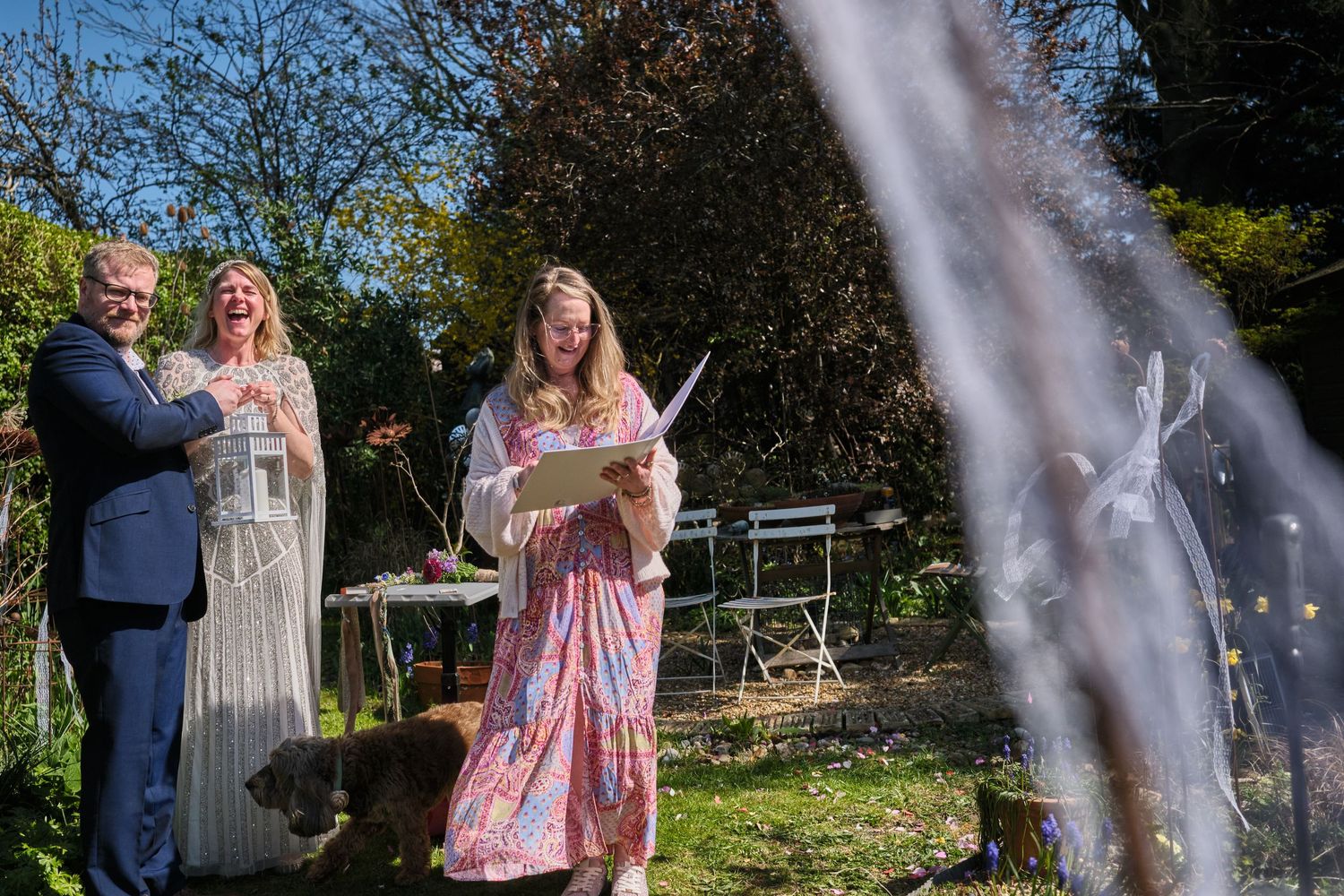 Wedding party celebration with confetti shower in a sunny garden setting.