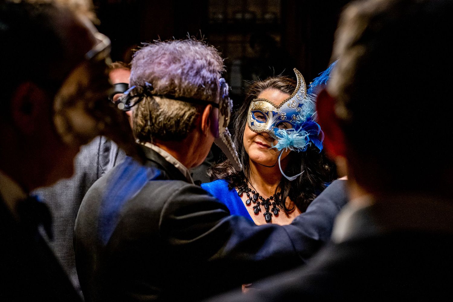 Guests mingle and socialize at an elegant evening event with dramatic lighting and shadows.