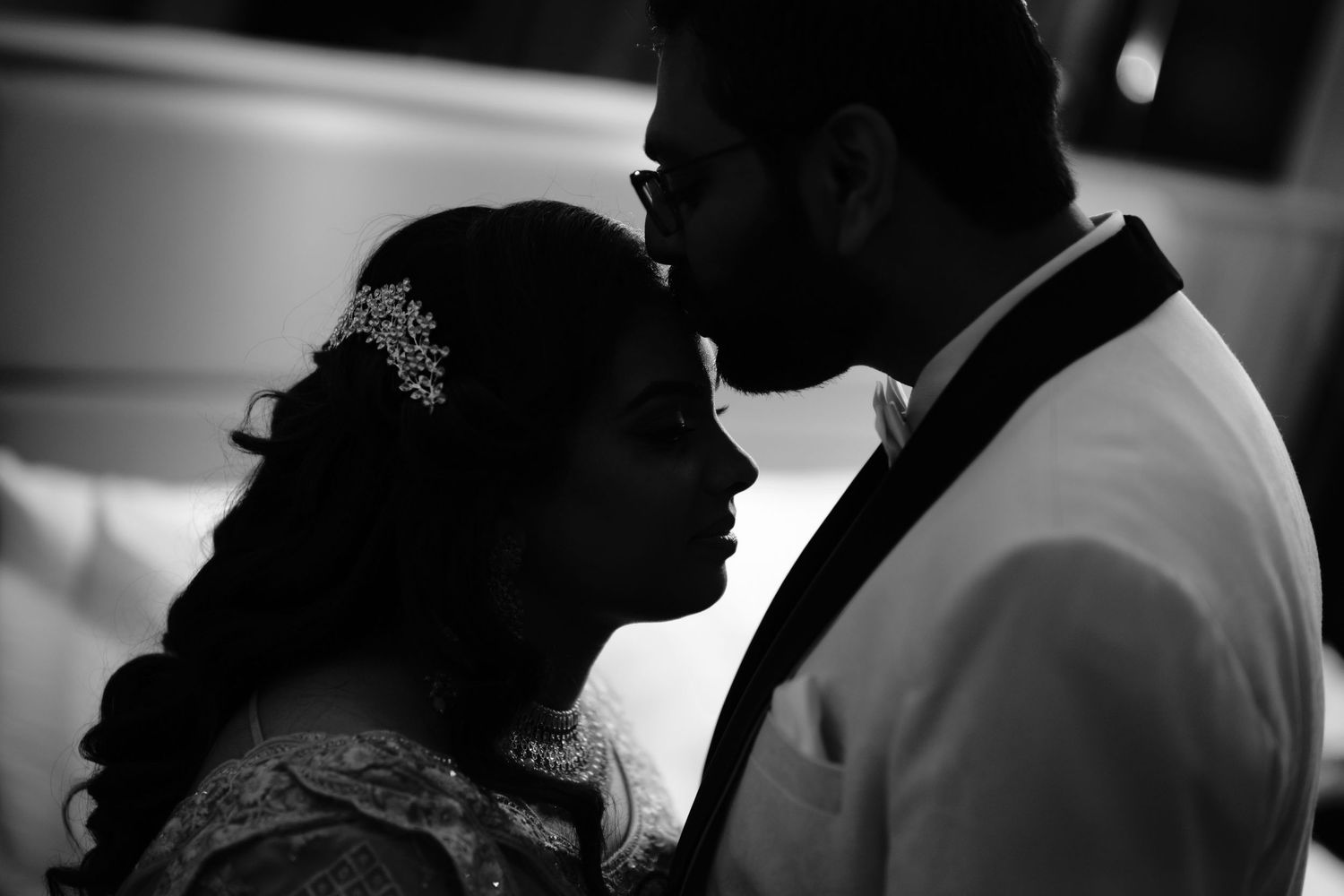 Intimate black and white silhouette of a couple in formal attire sharing a romantic moment.