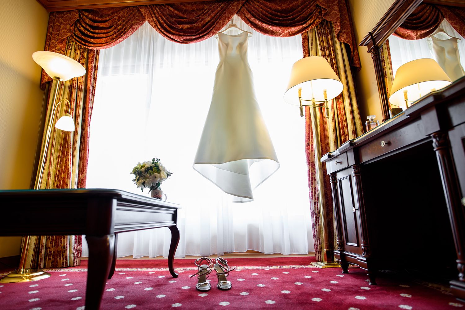 Classic hotel room with vintage furniture and dramatic red window treatments.