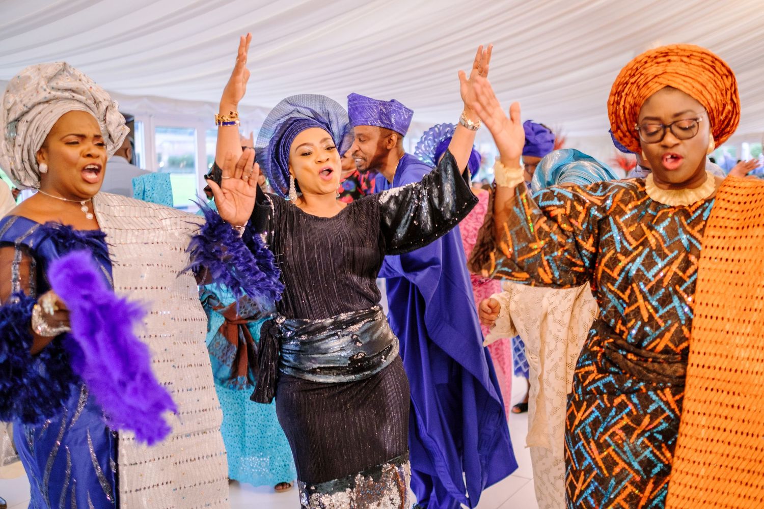 Joyful wedding guests in colorful traditional African attire dancing and celebrating at a festive reception.