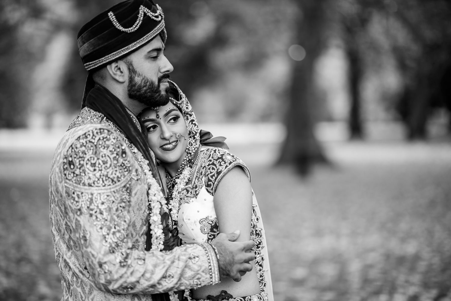 Black and white portrait of a couple sharing a joyful moment outdoors.