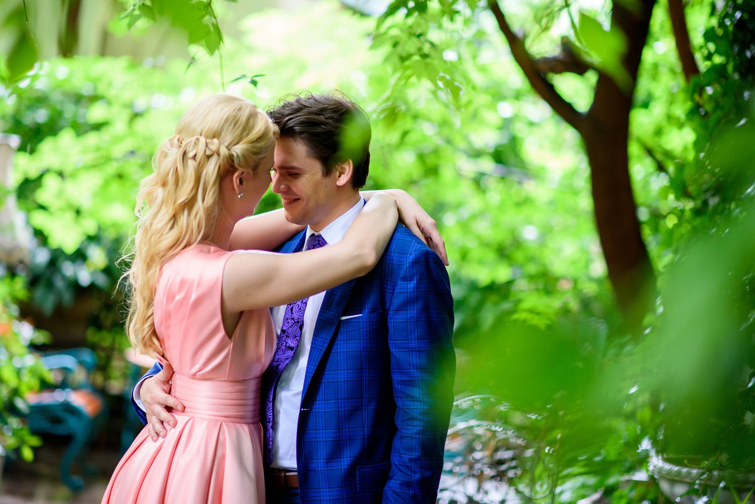 Garden engagement photo with soft focus and lush green foliage background.