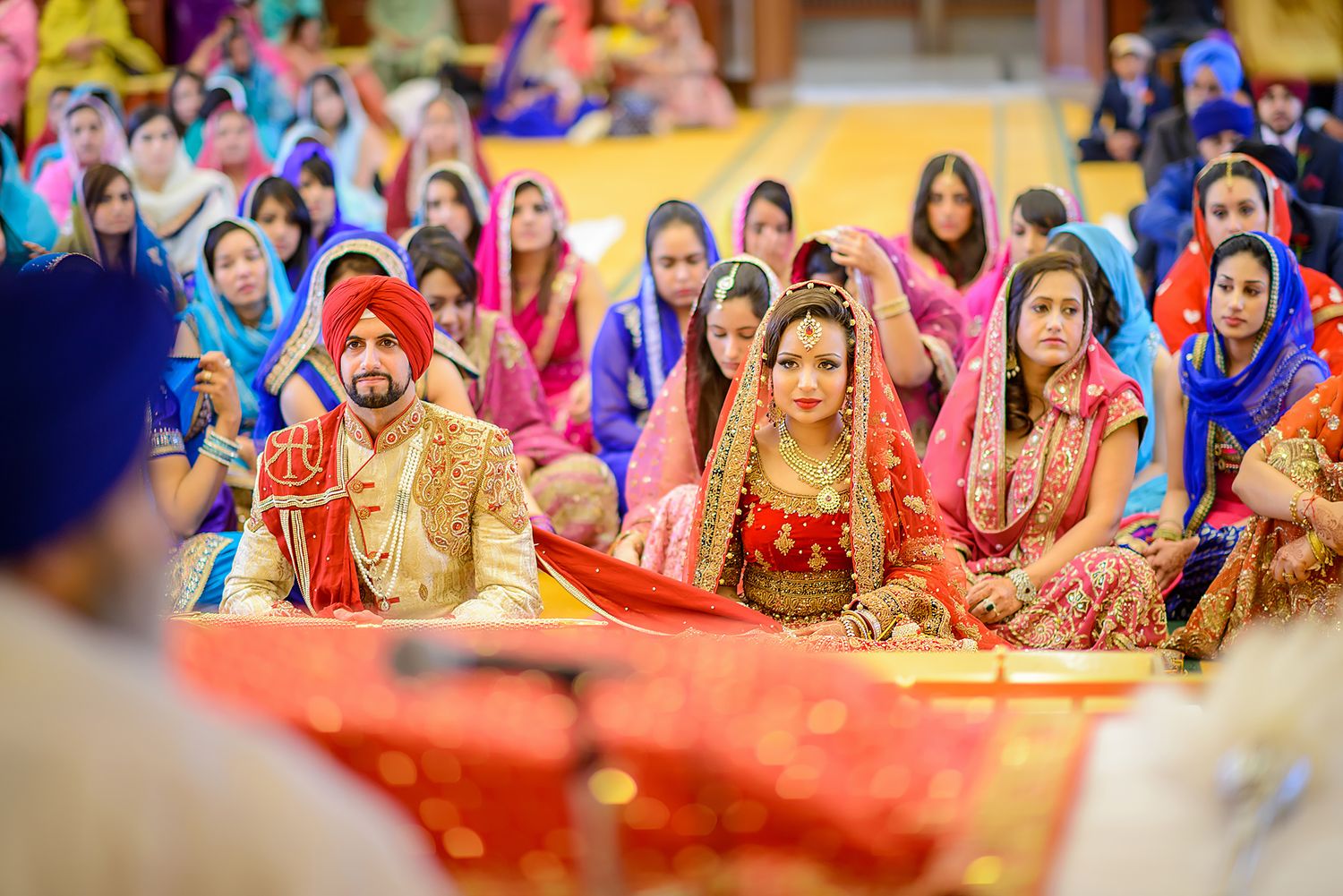 Colorful crowd of wedding guests in traditional Indian attire seated at a vibrant ceremony.