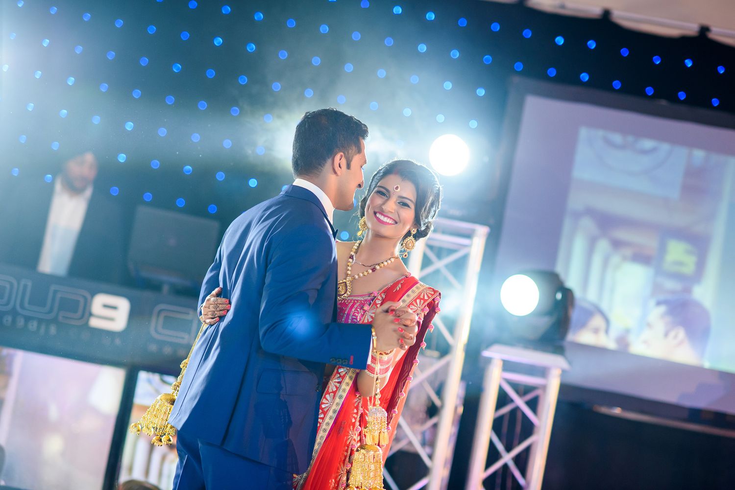 Wedding reception dance floor illuminated with blue spotlights and decorative lighting effects.