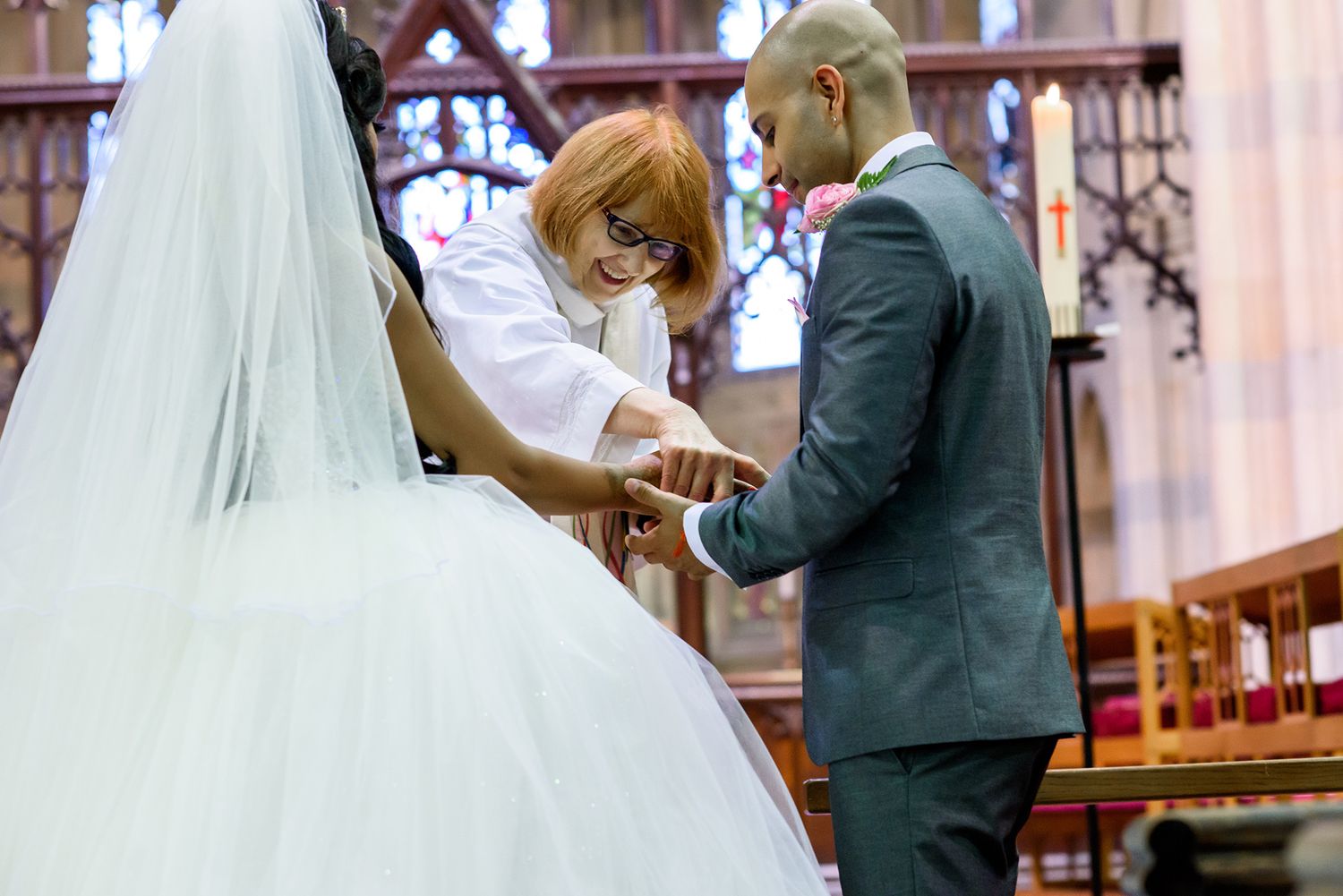Couple exchanging vows at the altar of a gothic church during wedding ceremony.