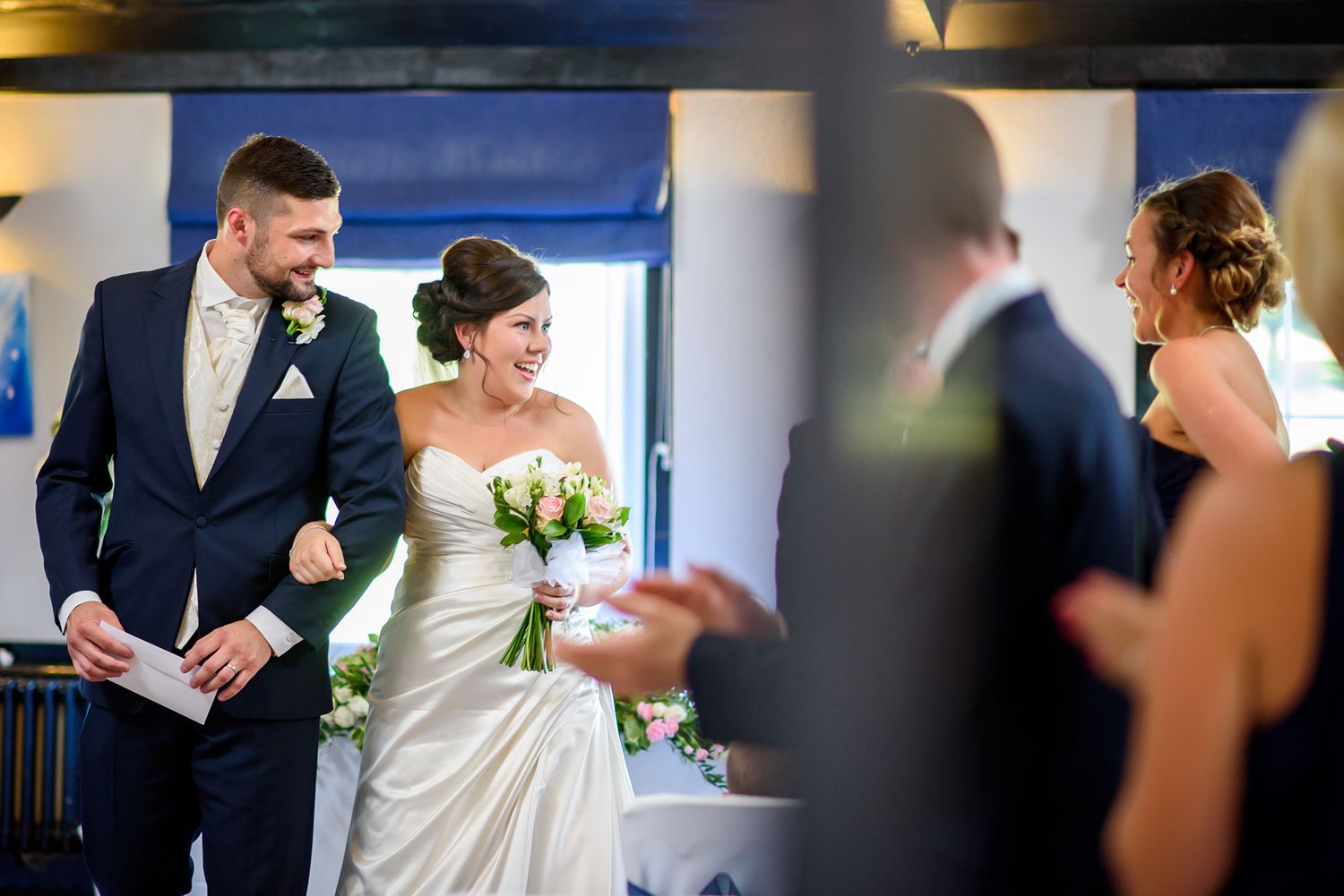 Elegant indoor wedding celebration with bridesmaids in navy dresses and bride in white gown.