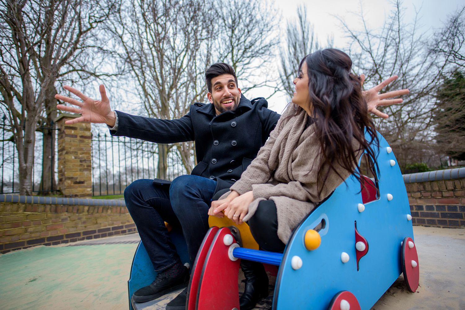 Playful interactions between two people near trees and benches outdoors.