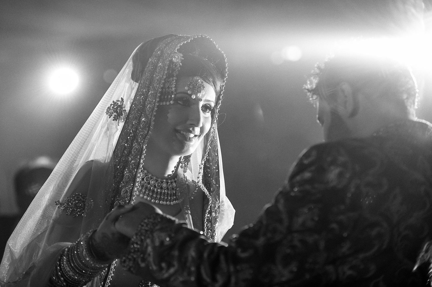 Dramatic black and white photo of bride in traditional veil during ceremony.