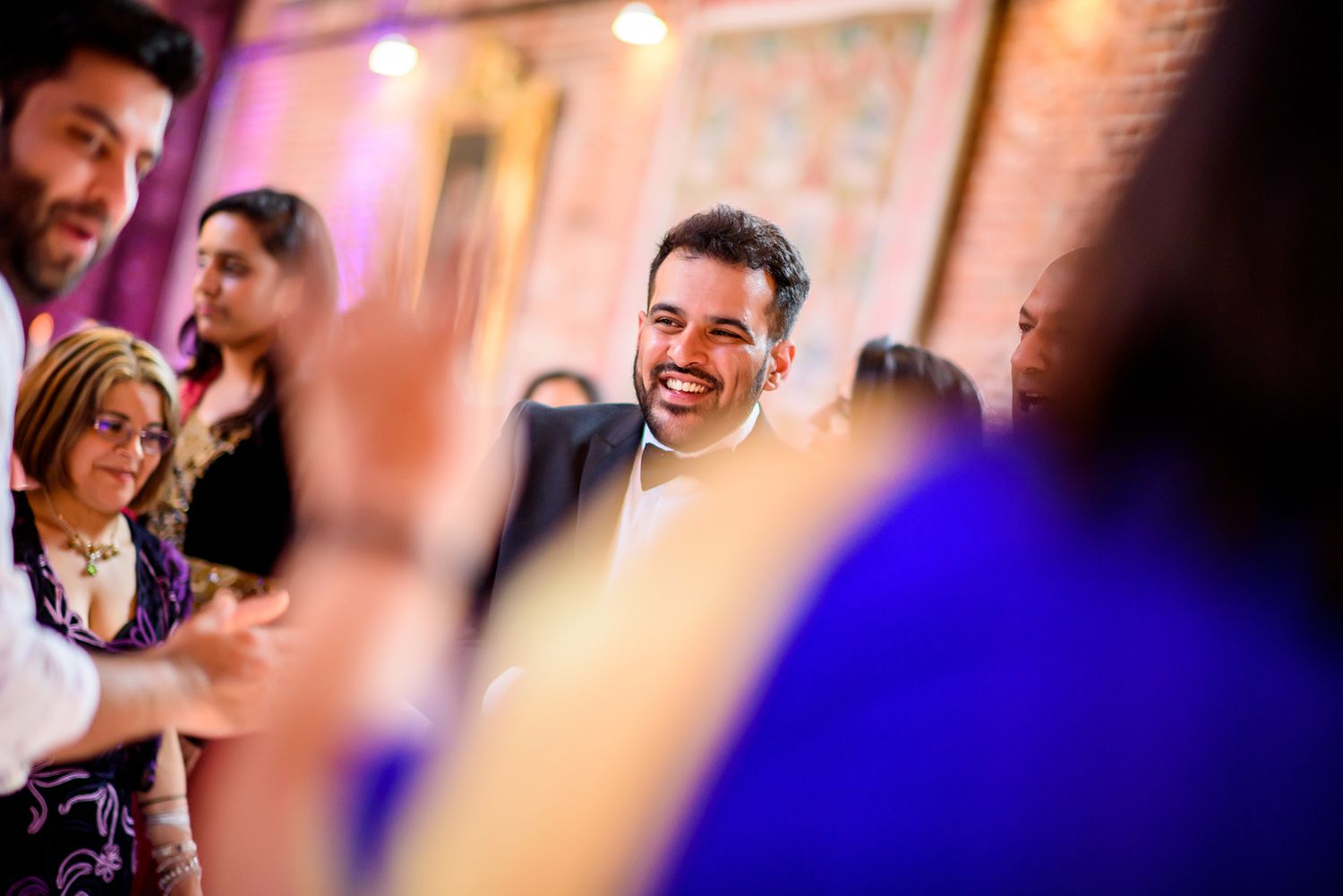 Reception guests enjoying a cheerful celebration with colorful ambient lighting.