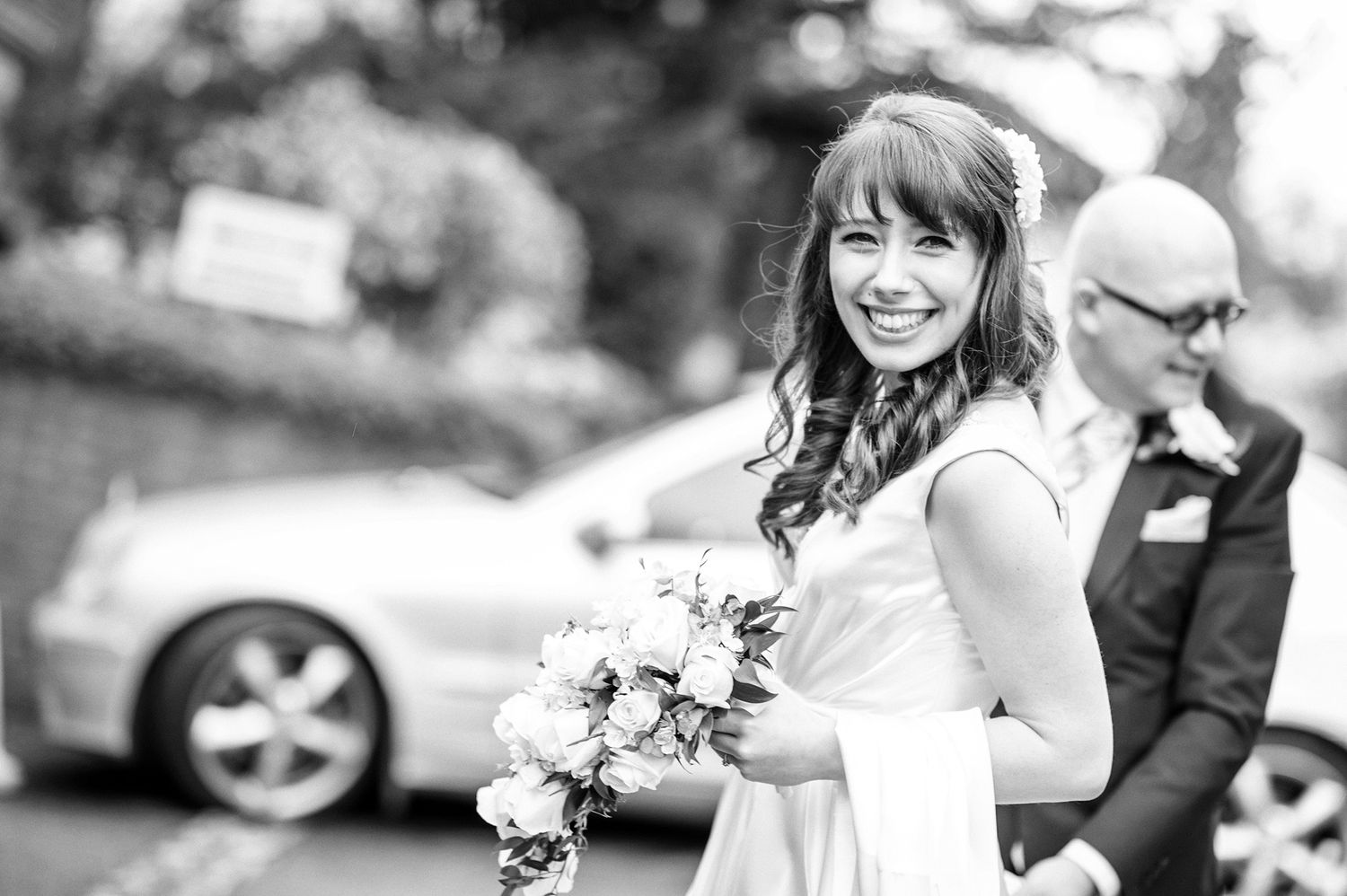 Candid black and white shot of guests celebrating at outdoor wedding reception.