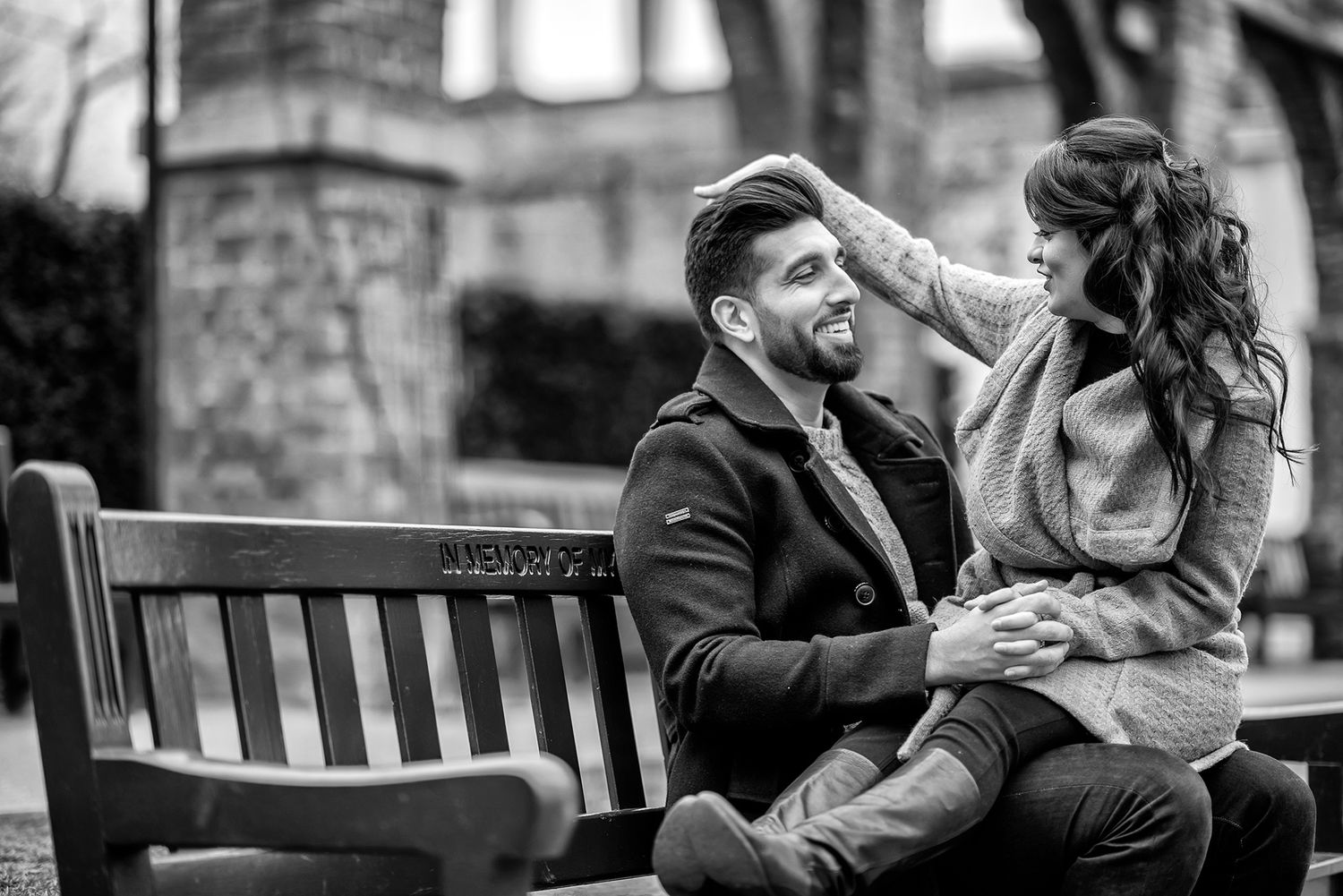 Couple sharing a tender moment while sitting together on a park bench on a cloudy day.