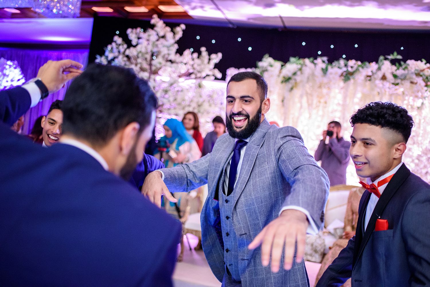 Wedding guests enjoying themselves at a reception with vibrant purple and blue lighting effects.