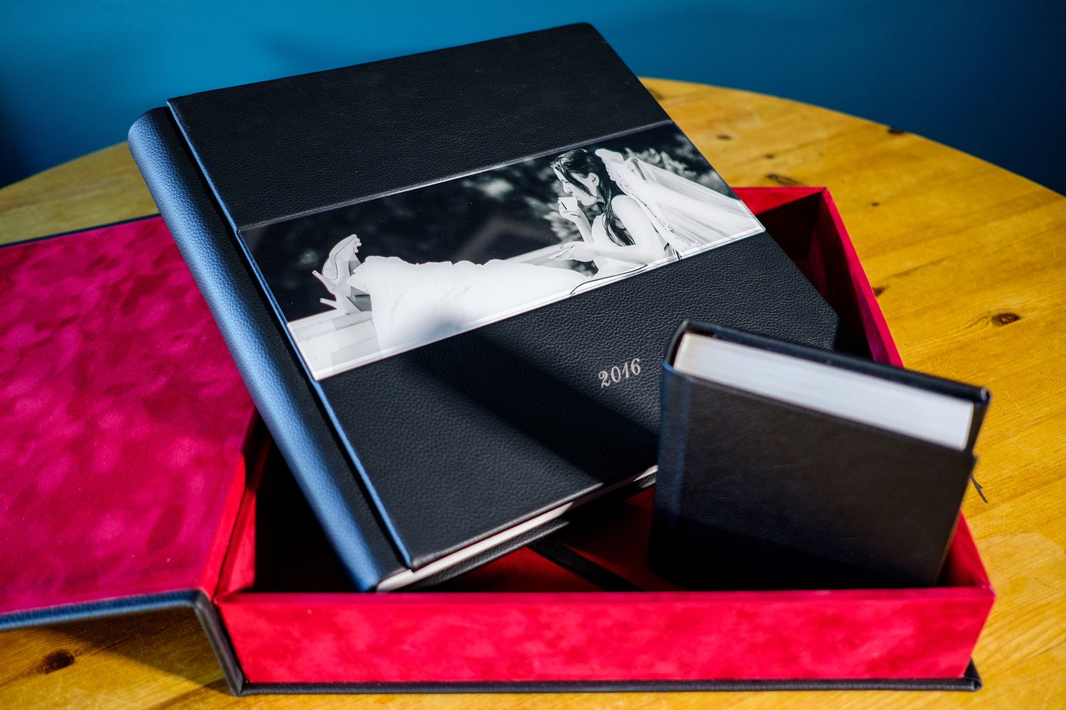 Collection of photo albums displayed on wooden surface with red and black colors.