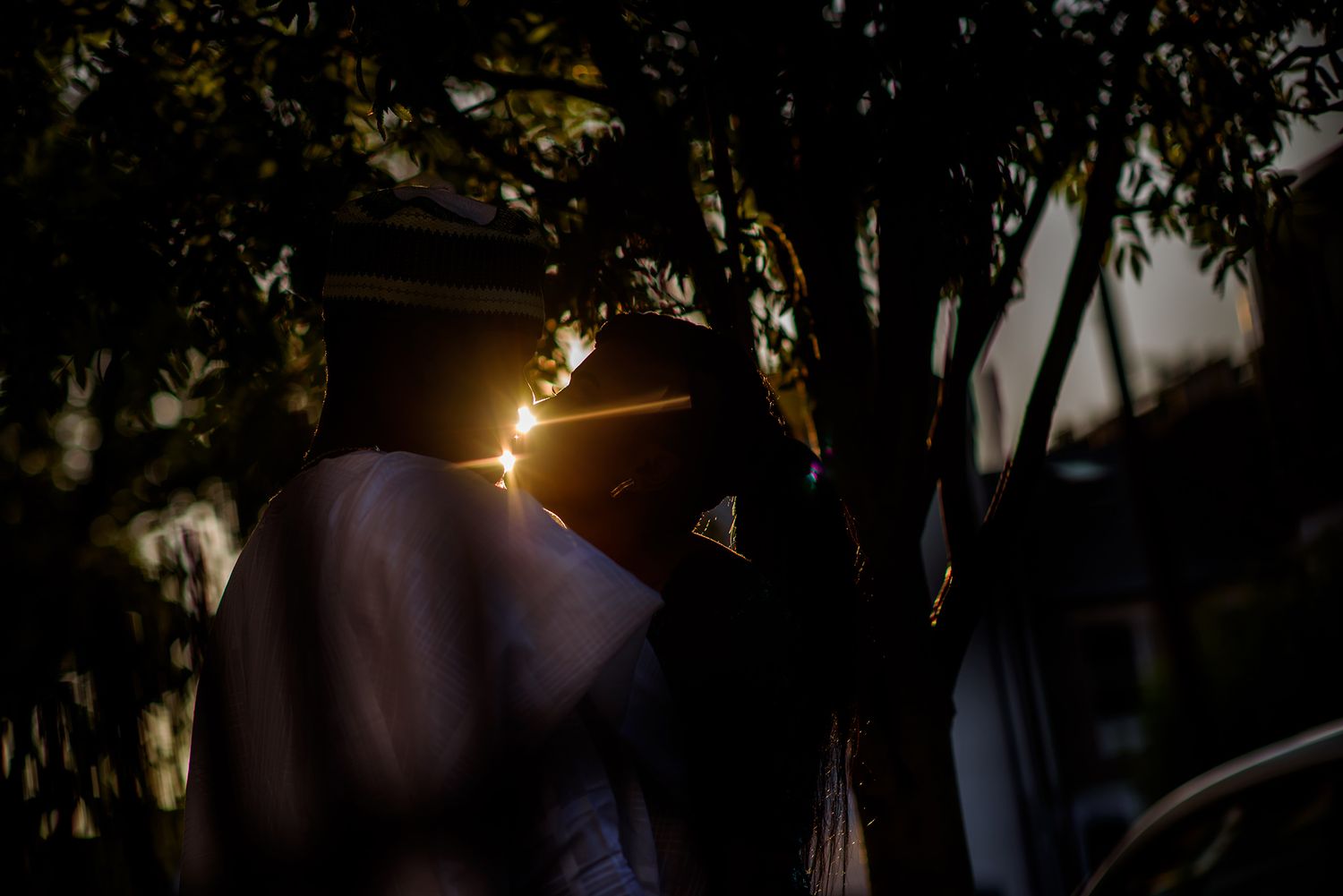 Dramatic black and white composition shows silhouettes against bright sunlight through trees.