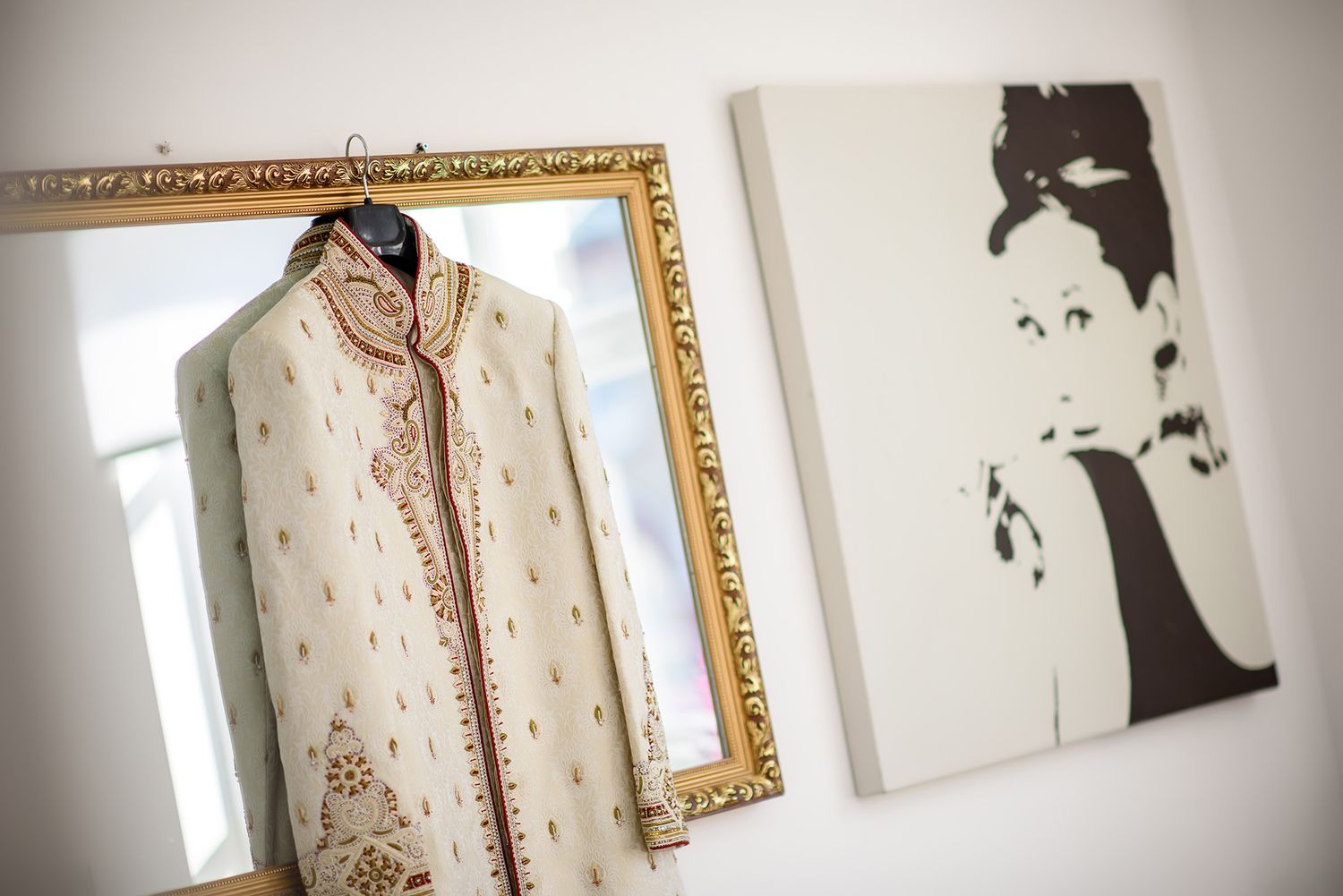An ornate traditional wedding outfit on display next to a classic portrait artwork.