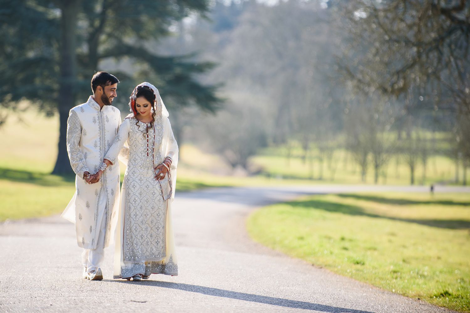 Elegant outdoor photo session showing traditional South Asian wedding attire in a park setting.