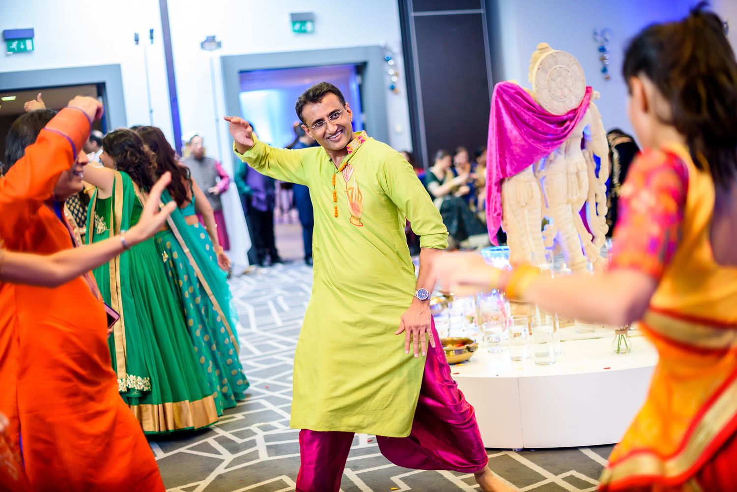 Dancers in vibrant yellow, orange and green outfits perform during a lively Indian celebration.