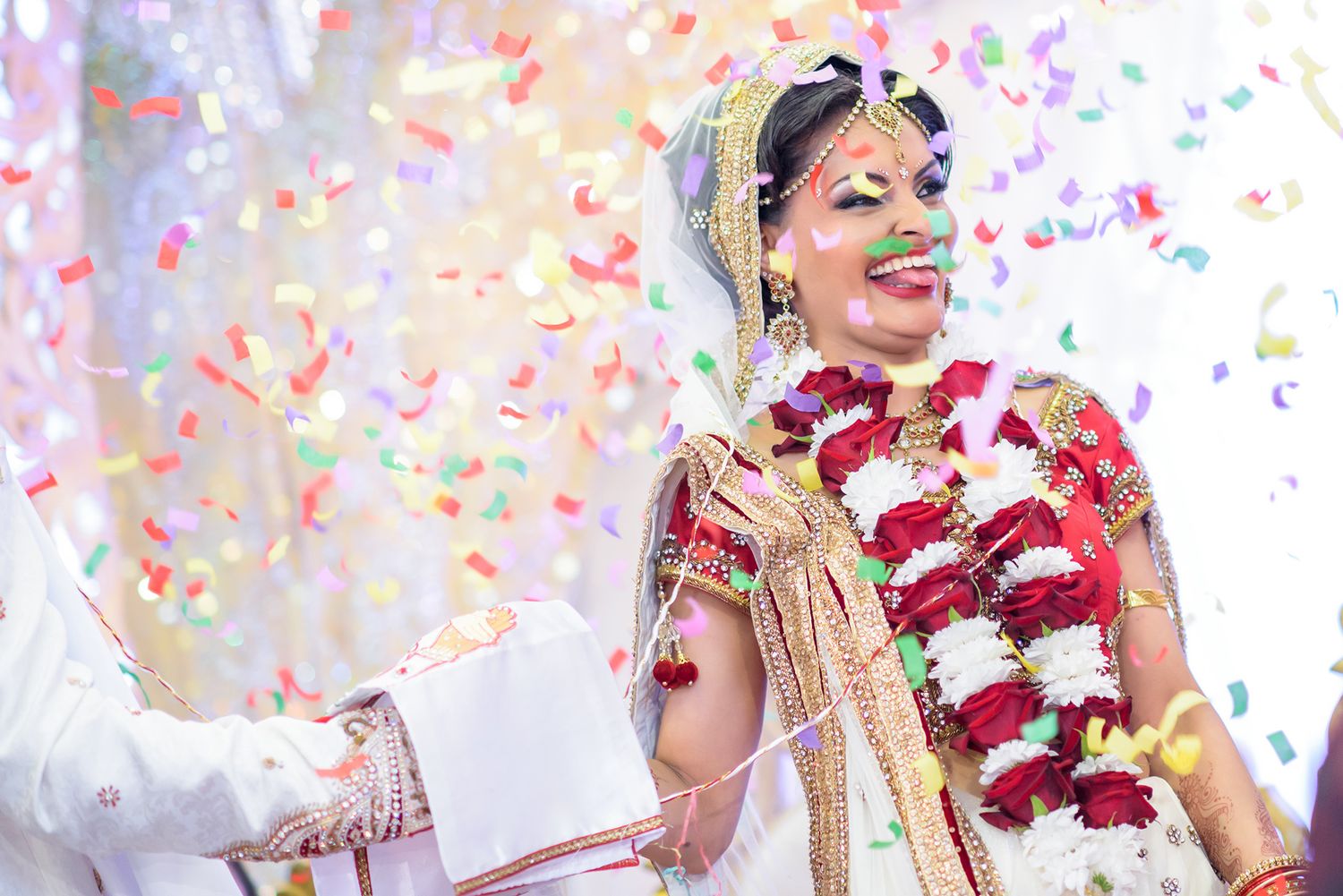 Joyous celebration with colorful confetti during traditional Indian wedding ceremony.