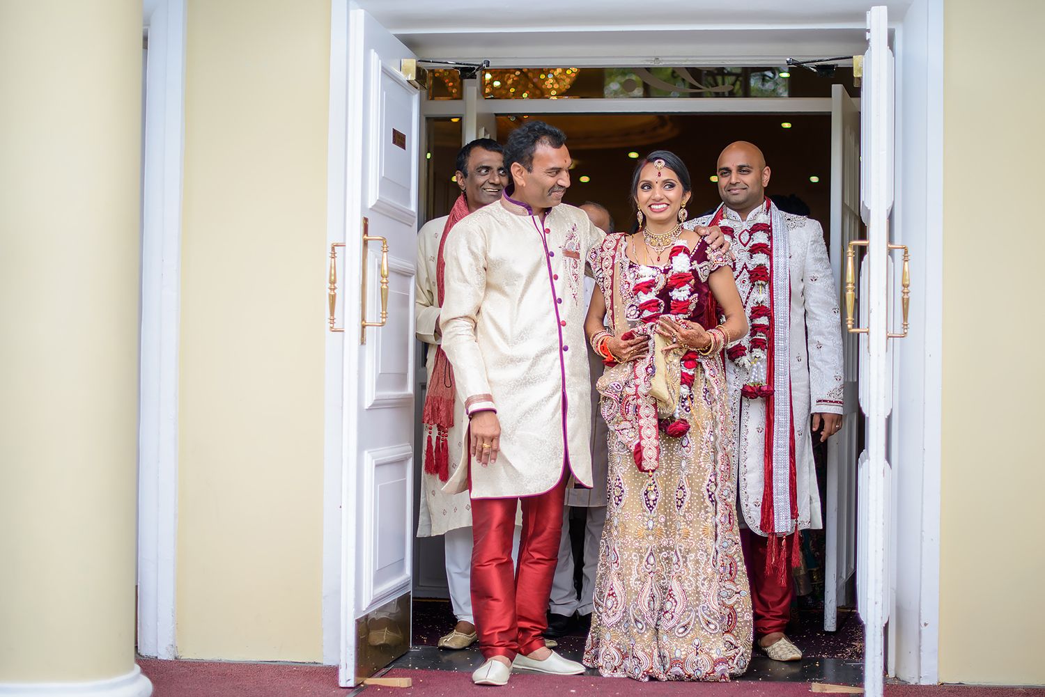 Wedding party gathering at an elegant venue entrance with cream colored walls.