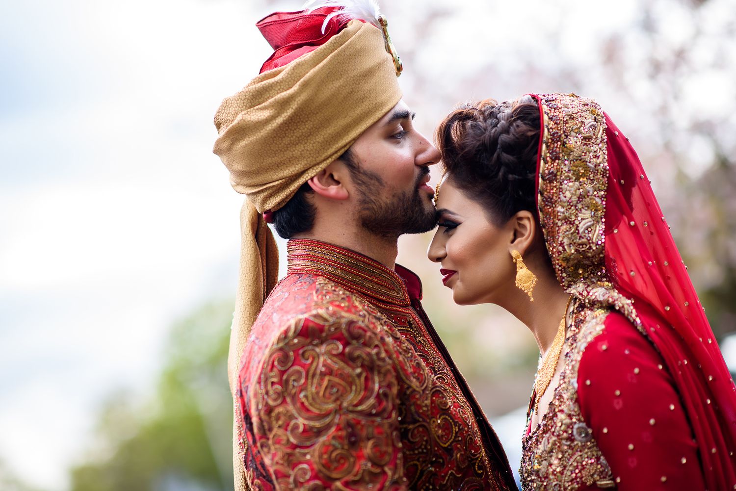 Romantic moment captured between newlyweds in traditional South Asian wedding outfits.