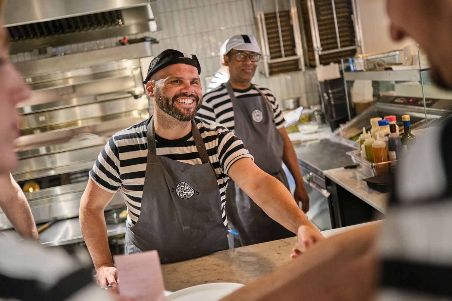 Kitchen staff preparing pizzas in a bustling restaurant kitchen.