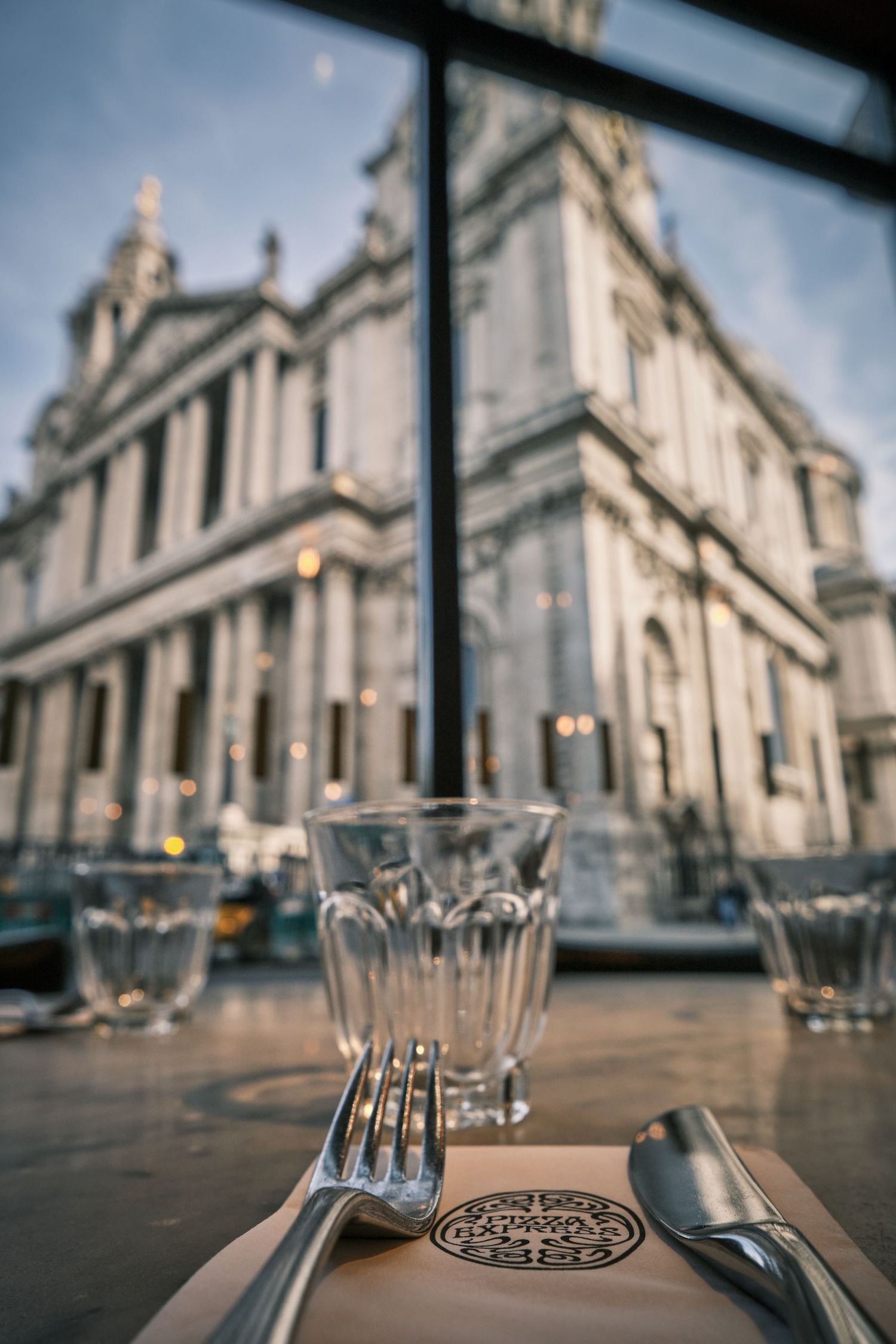 Place settings with silverware arranged on tables with a grand cathedral building visible in the background.