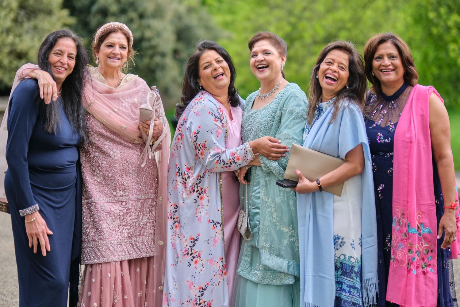 A group of friends in colorful traditional attire sharing a joyful moment together outdoors.