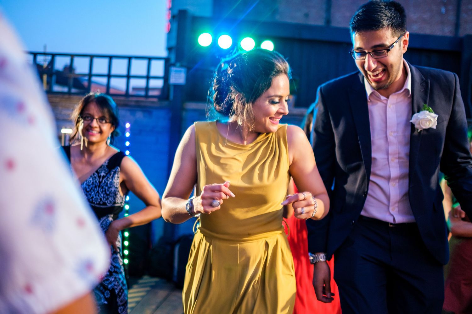 Wedding reception dance party with blue lighting and guests dancing in formal attire.