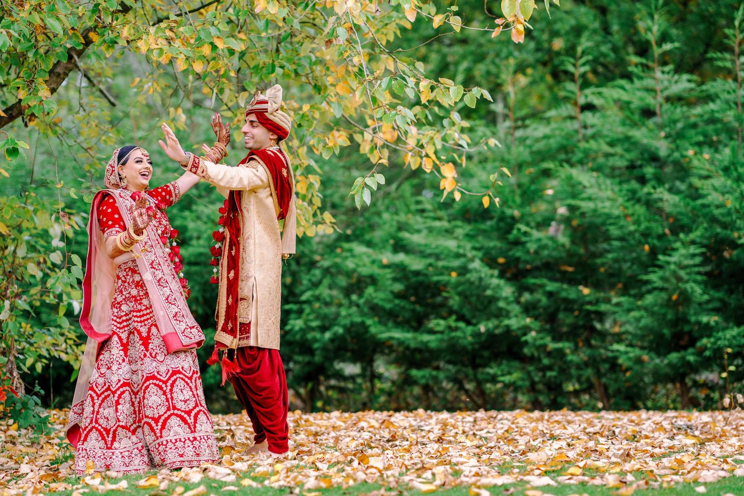 Autumn wedding photoshoot with yellow fallen leaves and greenery in an outdoor setting.