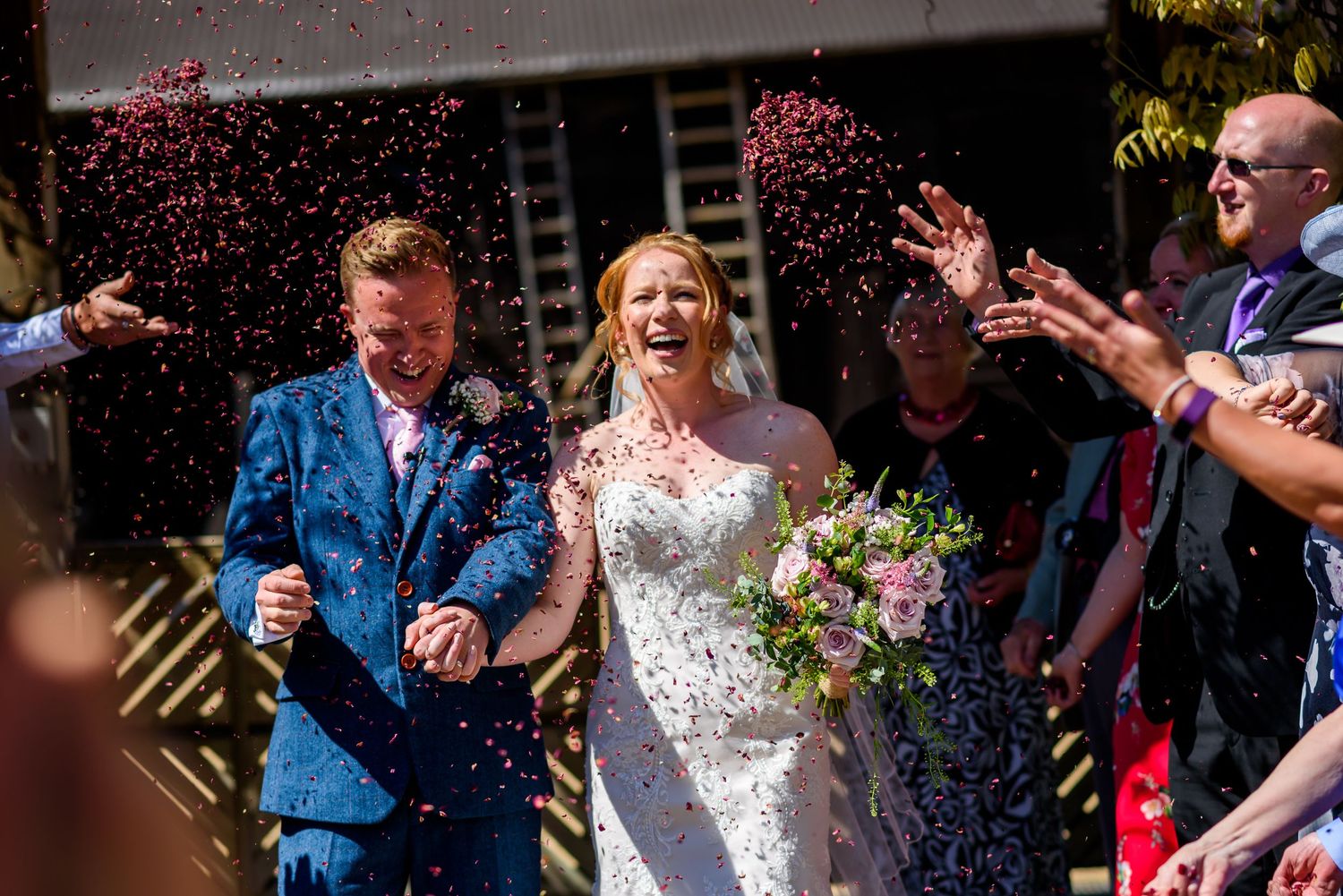 Confetti fills the air during an outdoor wedding celebration.
