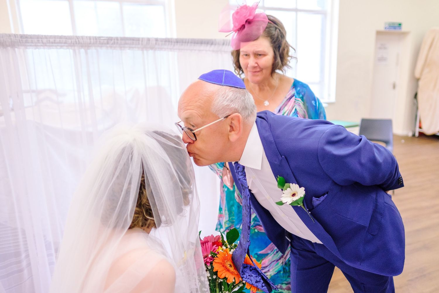 Wedding celebration moment captured in bright indoor setting with festive decorations.