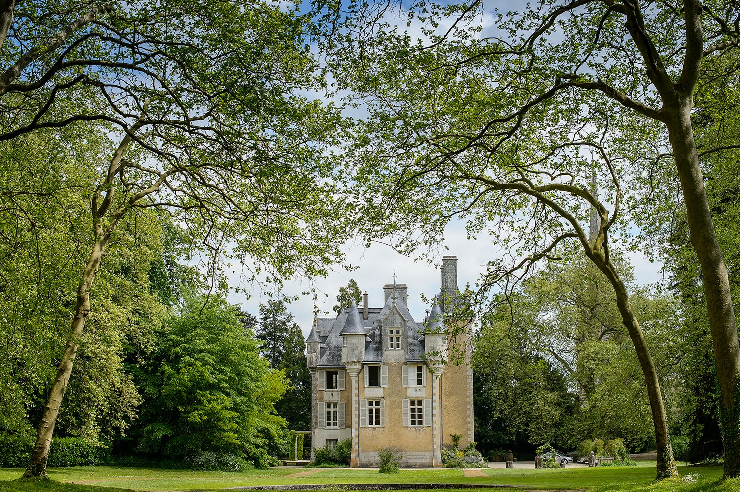 Scenic panorama of a historic manor building surrounded by lush green trees.