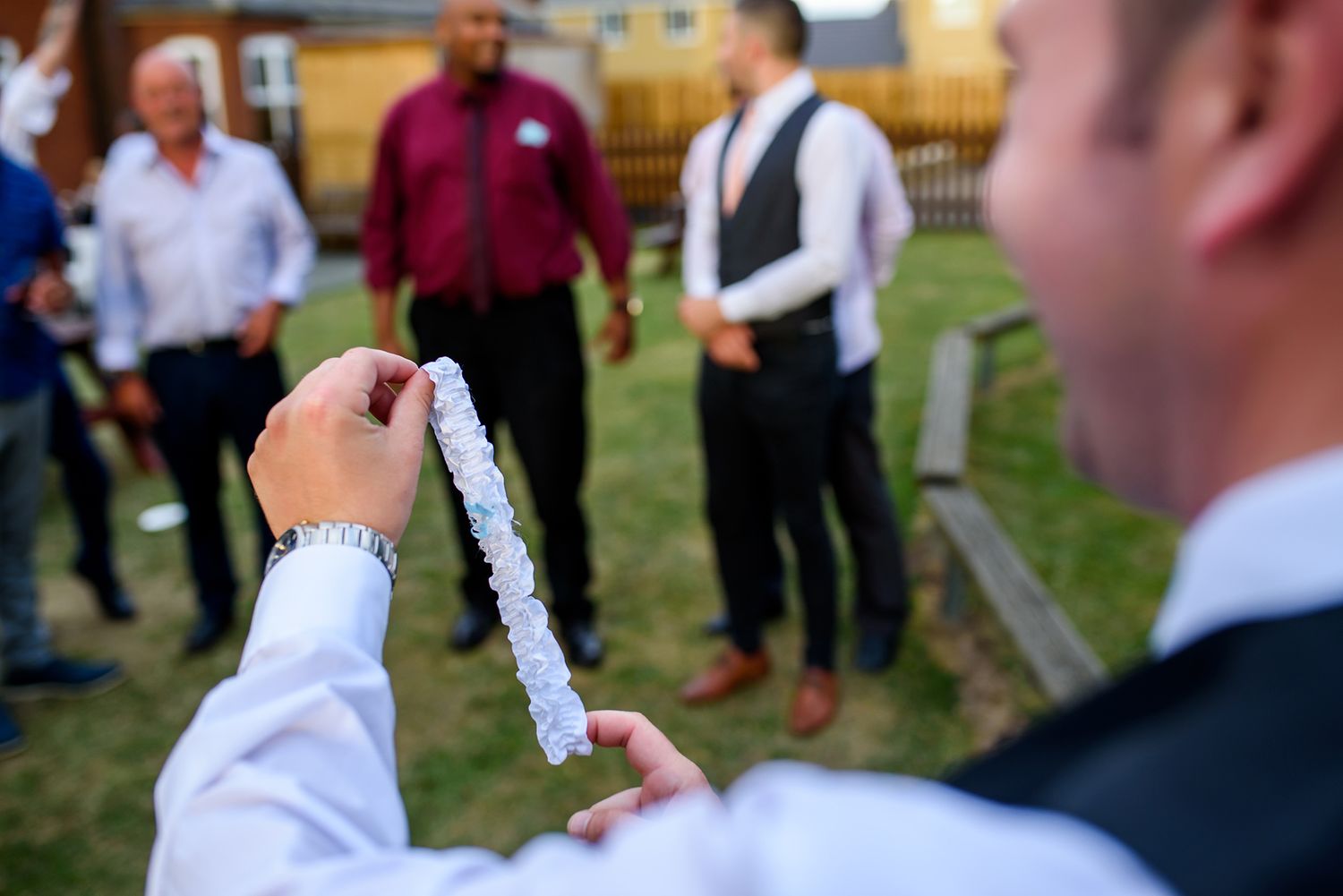 Wedding party members mingle and socialize outdoors during cocktail hour in formal attire.