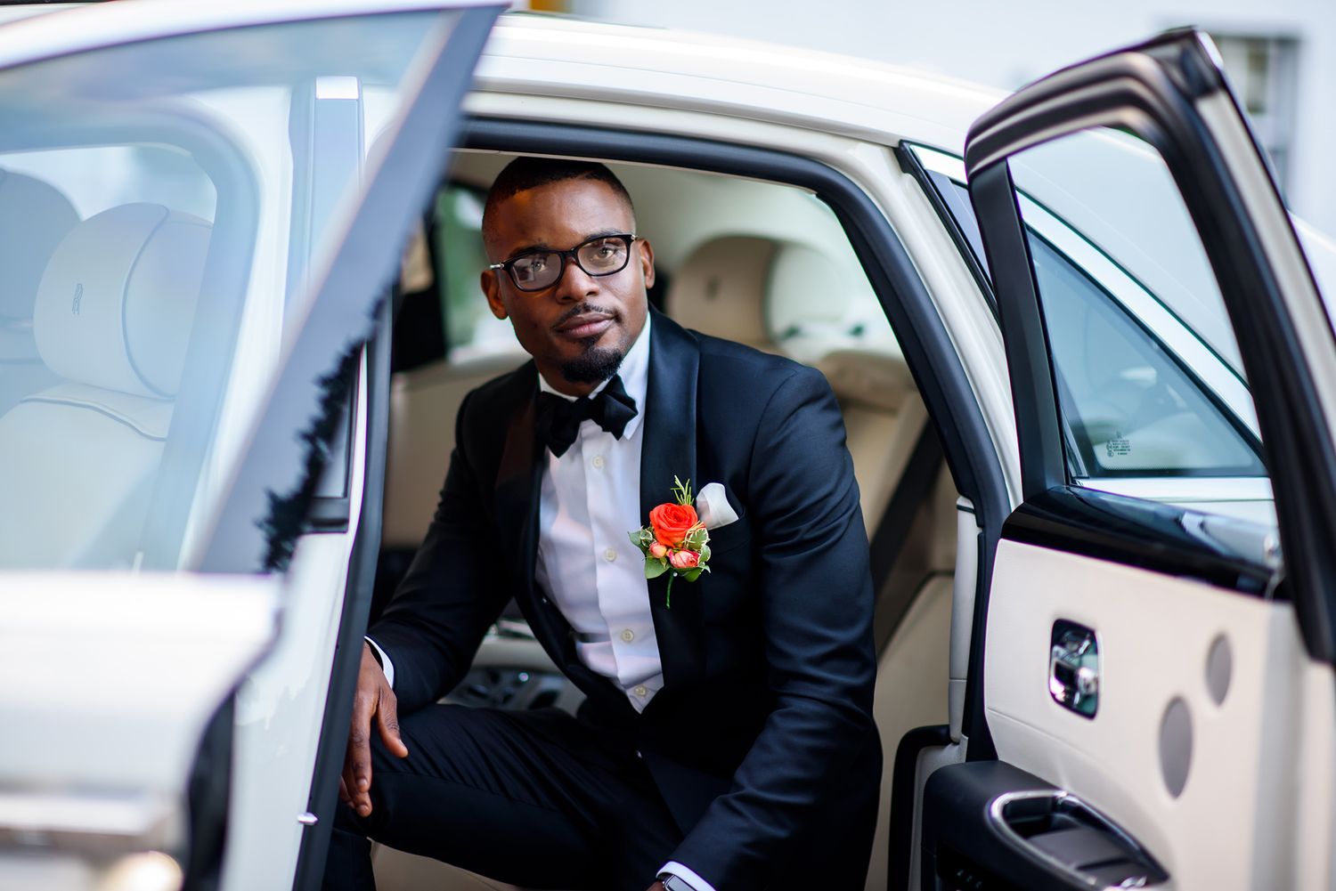 Groom steps into luxury car while wearing classic black tuxedo on wedding day.
