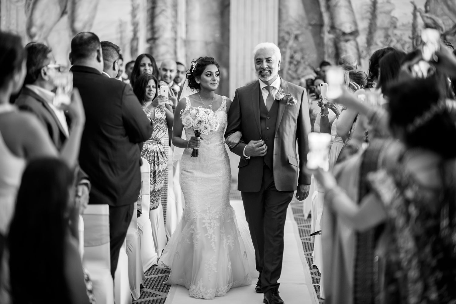 Black and white wedding ceremony moment with gathered guests and white floral decor.