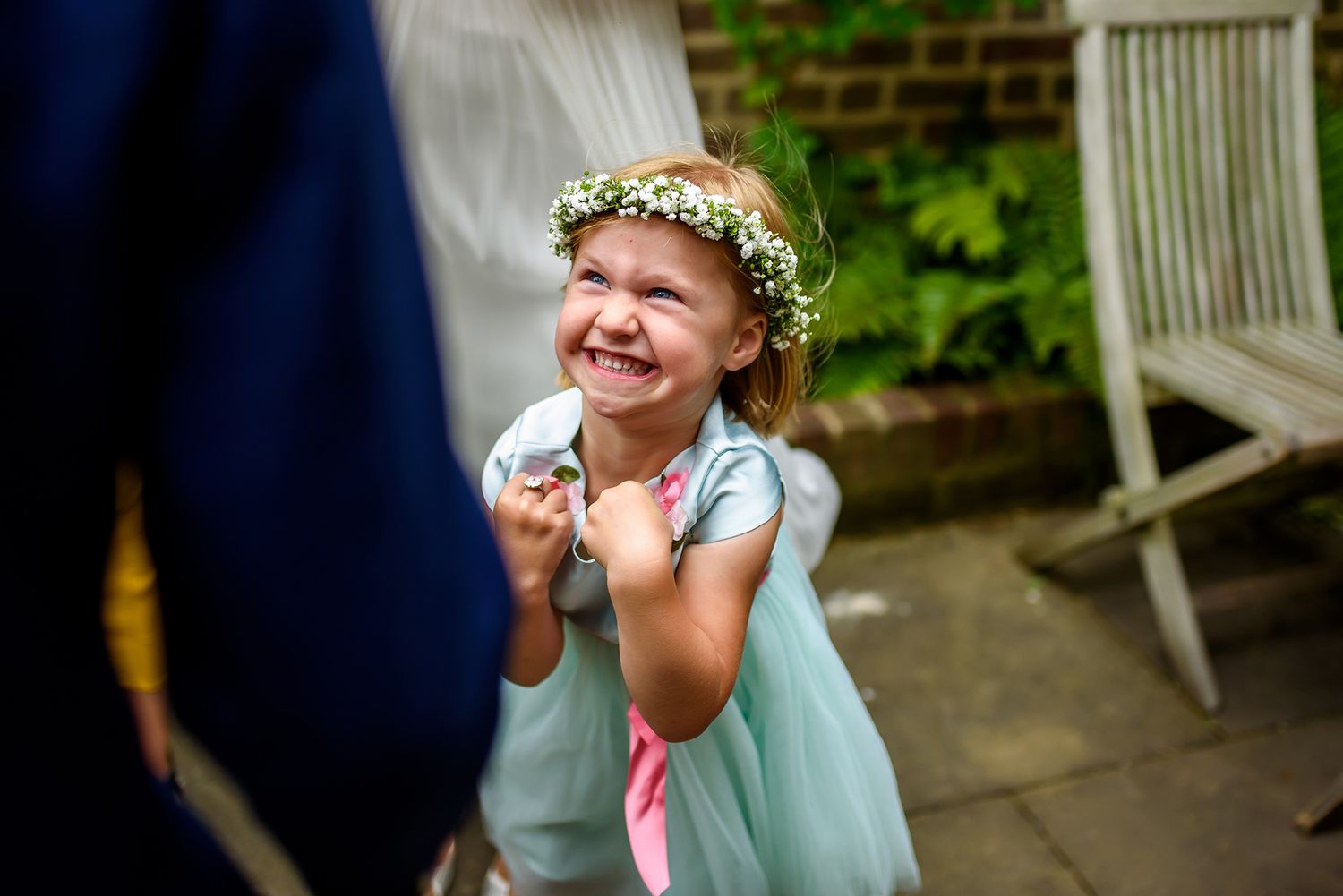 A flower girl in a mint dress and floral crown giggles with excitement.