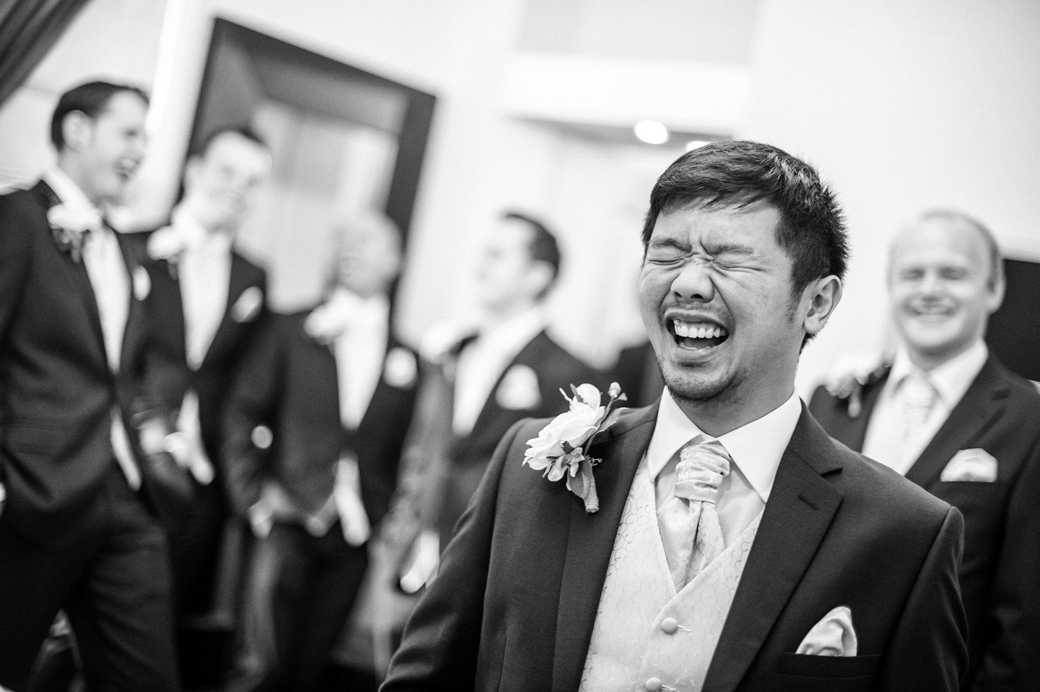 Black and white candid of wedding guests laughing during celebration.