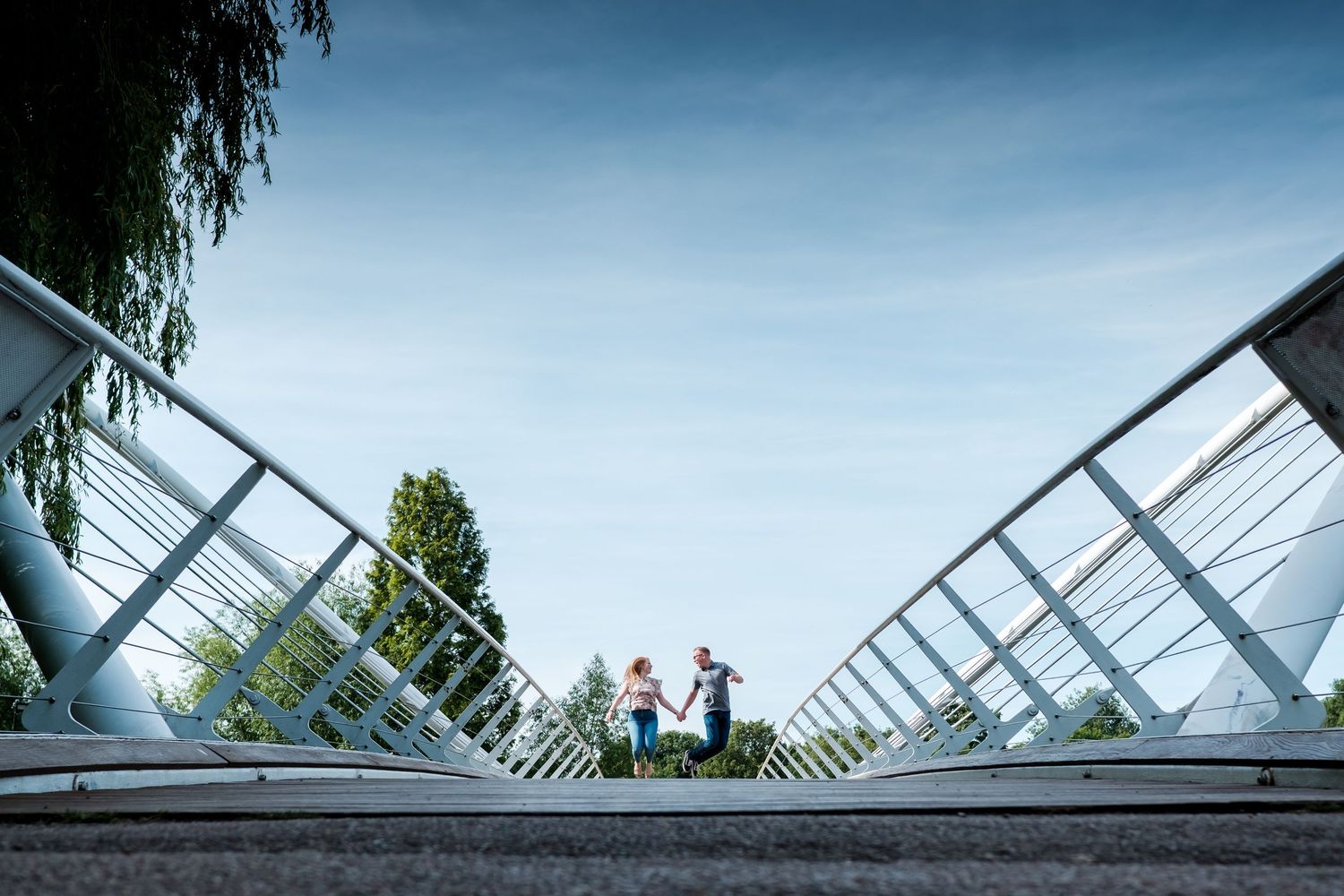 Modern bridge with geometric railings shot from a low angle against blue sky.