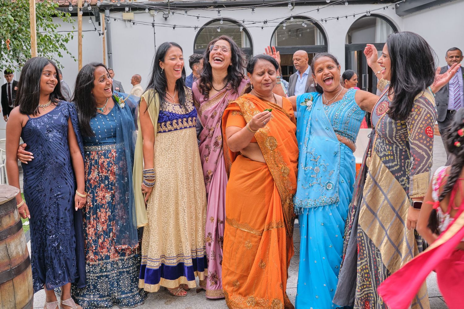 Guests in colorful traditional Indian attire celebrate at an outdoor gathering.