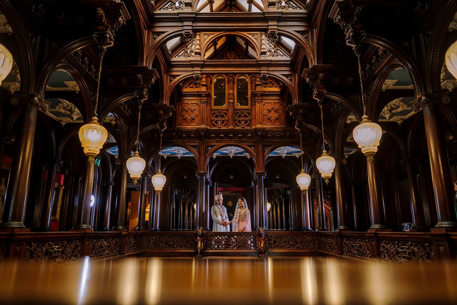 Elegant ballroom interior with ornate wooden ceiling details and hanging crystal chandeliers.
