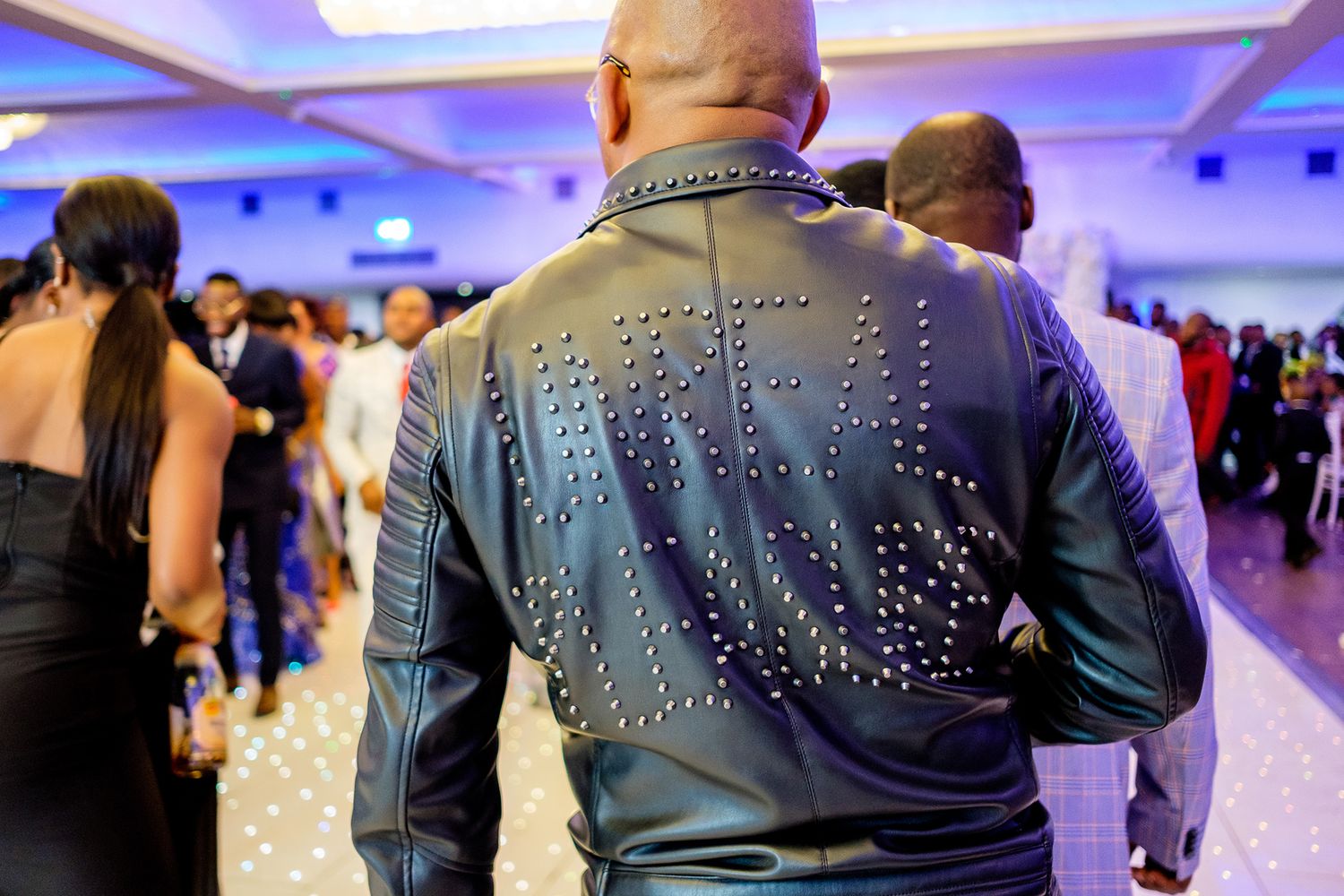 Back view of guest wearing embellished leather jacket at wedding reception.