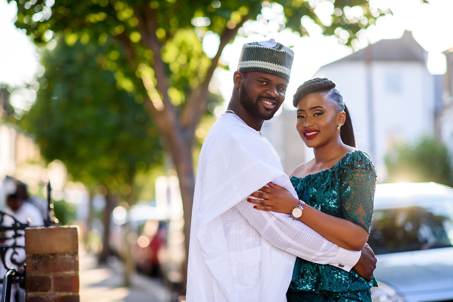 A couple shares a tender moment outdoors, with the person in teal dress smiling brightly.